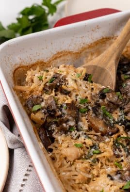 a wooden spoon scooping chicken marsala rice casserole out of a red baking dish