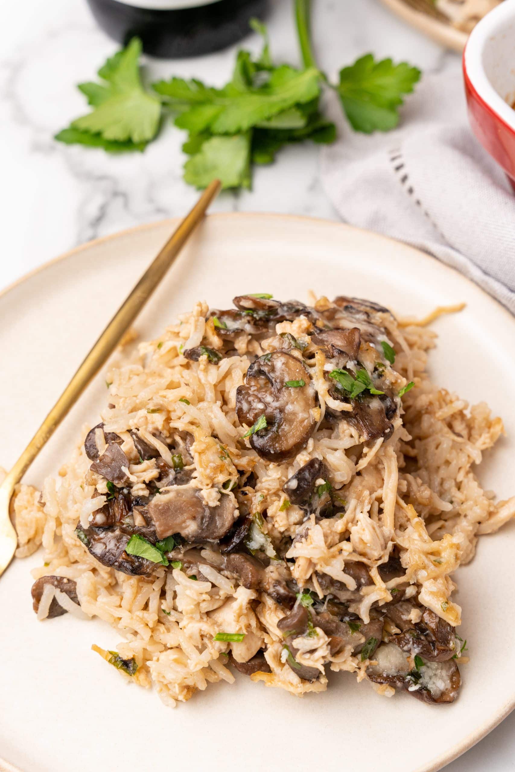 chicken marsala and rice casserole served on white plates with a golden fork on the side