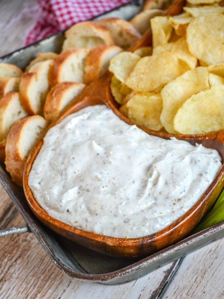 Montreal Steak Seasoning Dip served in a teak bowl with chips, sliced bread, and veggies for dipping