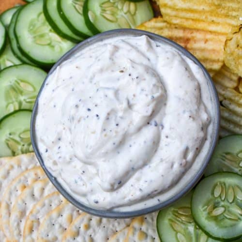 montreal steak seasoning dip in a small gray bowl surrounded by chips and crackers