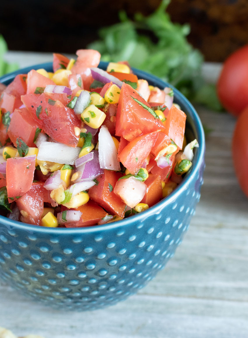 PICO AND CORN SALSA IN A SMALL BLUE BOWL ON A WOODEN TABLE