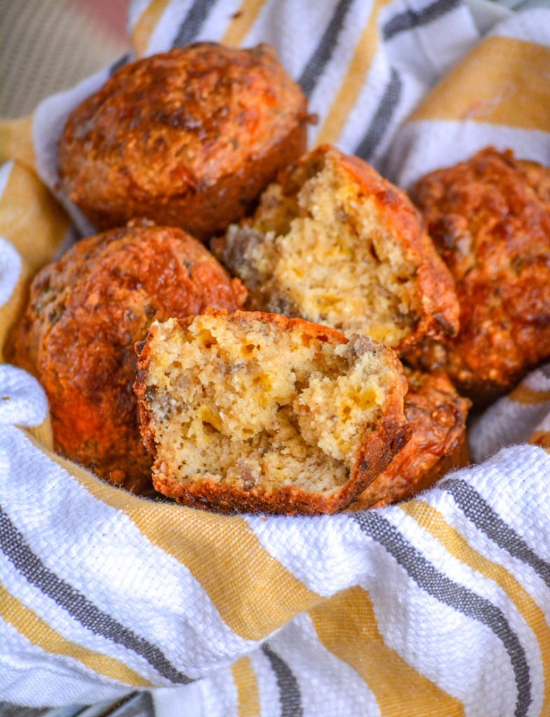 golden brown sausage egg and cheese muffins with grits are opened and in a cloth inside a basket