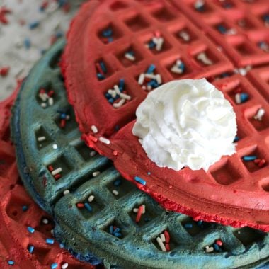 a dollop of whipped cream on red white and blue stacked waffles