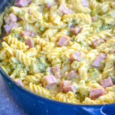 cheesy ham and broccoli pasta in a blue cast iron skillet