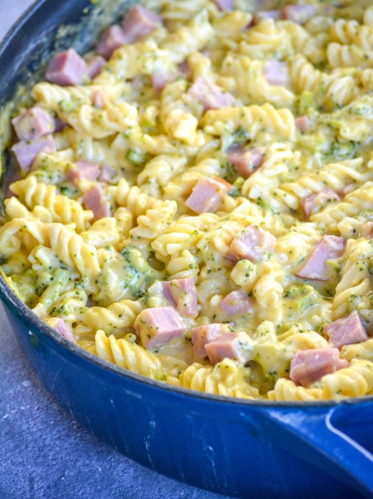 cheesy ham and broccoli pasta in a blue cast iron skillet