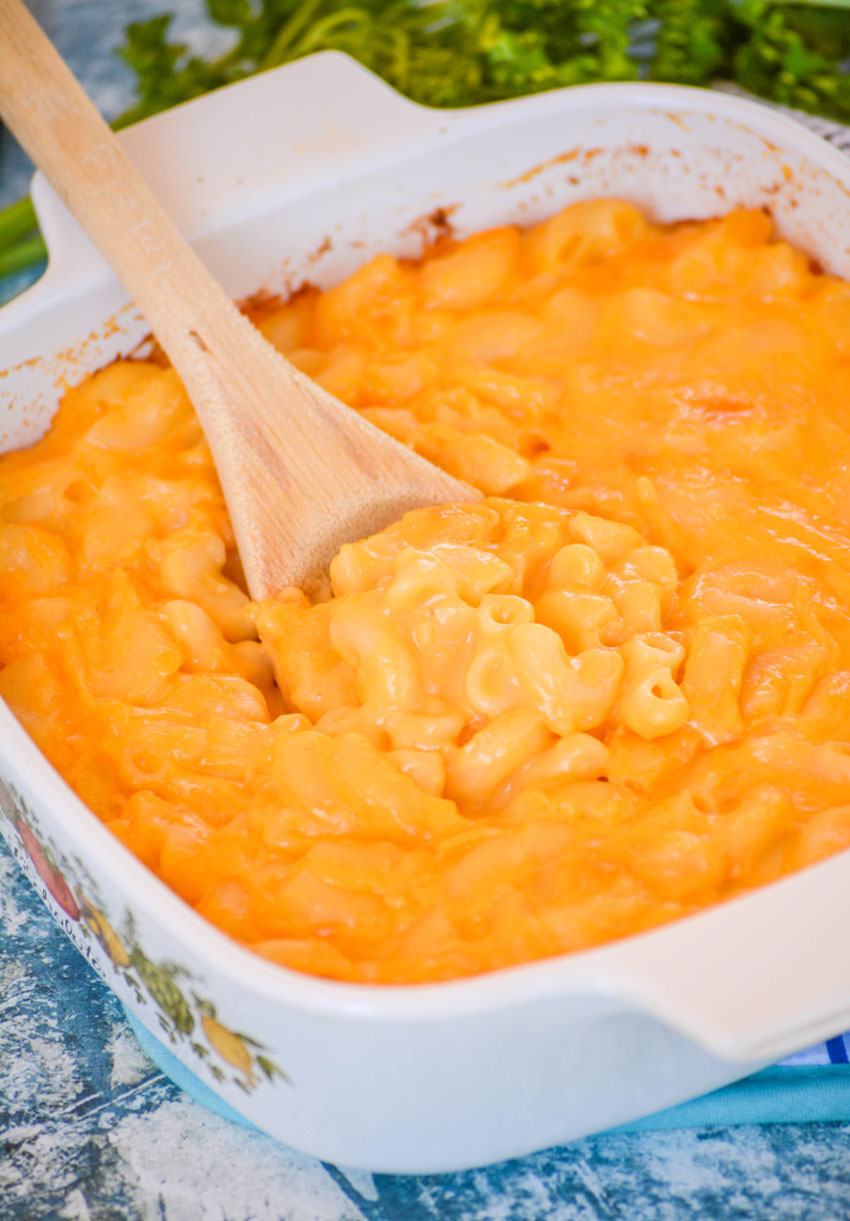 a wooden spoon scooping copycat stouffers mac and cheese out of a small white pyrex dish