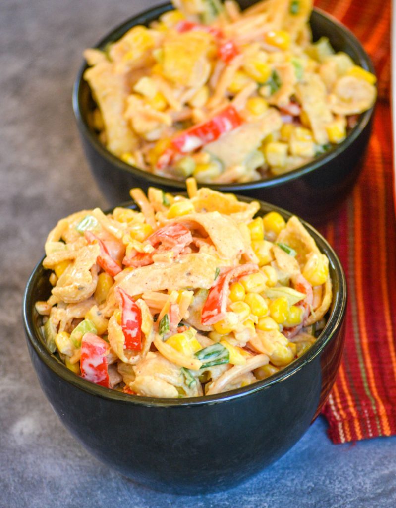 two black bowls full of crunchy corn salad, studded with fritos corn chips