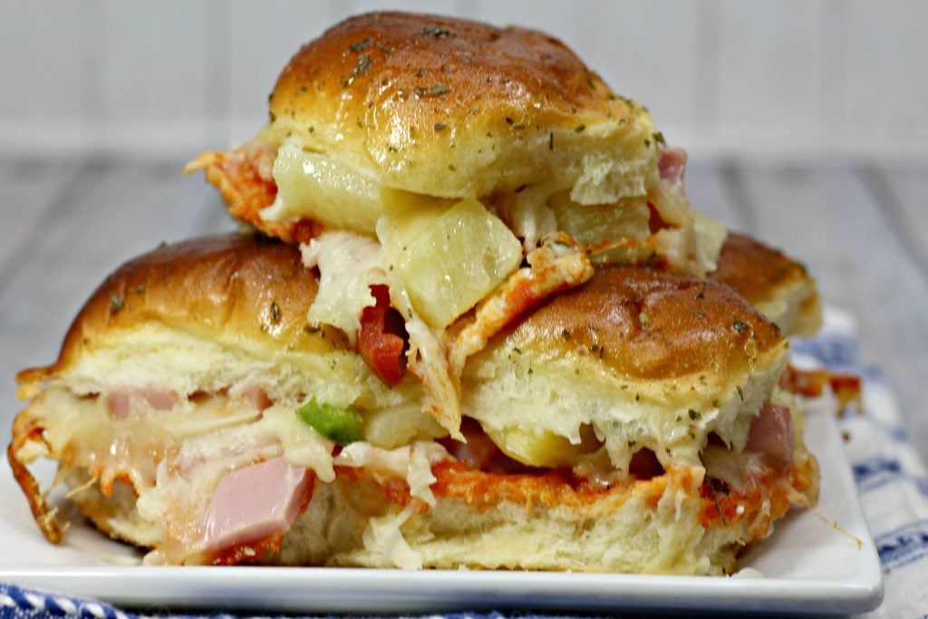 Hawaiian pizza sliders stacked on a white serving plate