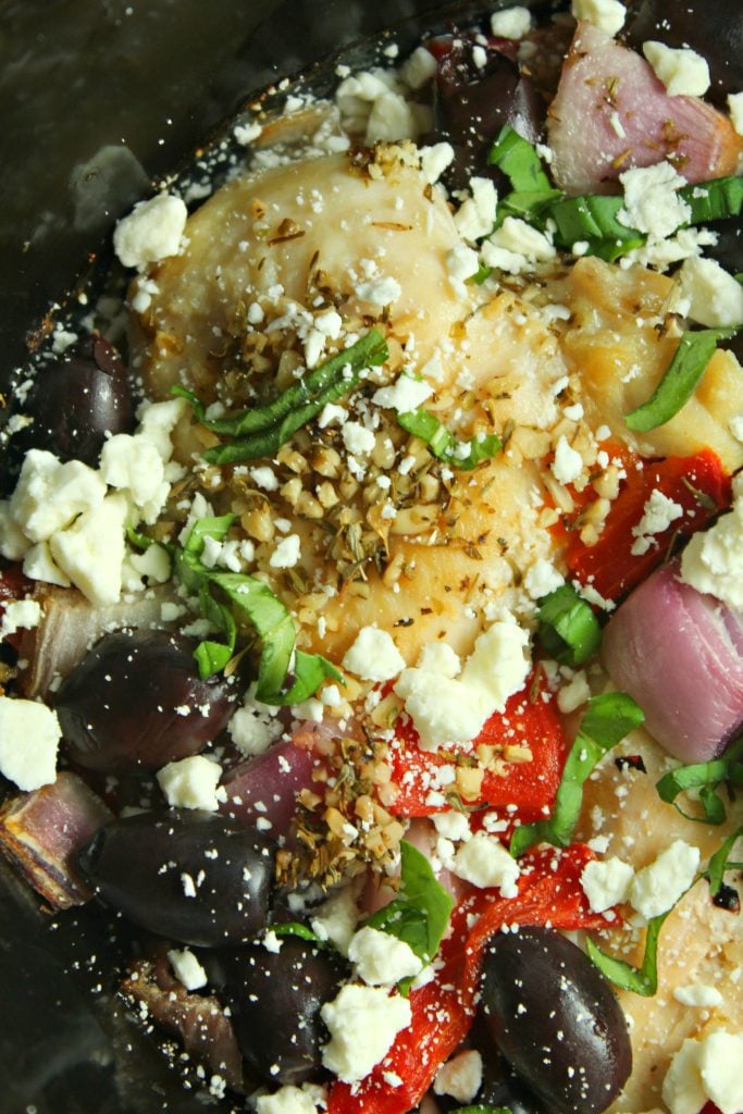 Greek chicken with feta cheese & fresh veggies in the black bowl of a family crockpot