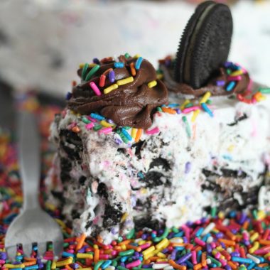 a slice of oreo funfetti icebox cake sitting on rainbow sprinkles