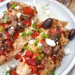 slow cooker greek chicken over steamed white rice on a gray dinner plate