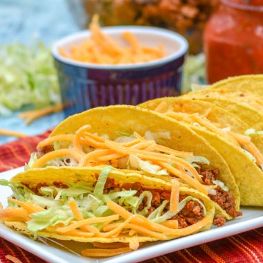 ground beef tacos stuffed and lined up on a white serving platter