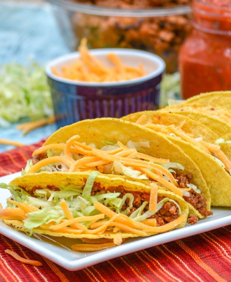 ground beef tacos stuffed and lined up on a white serving platter