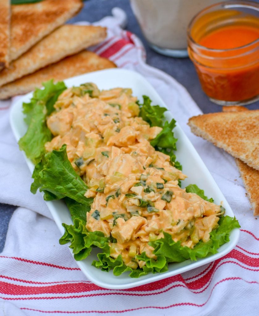 buffalo ranch chicken salad on a bed of green leaf lettuce on a white platter