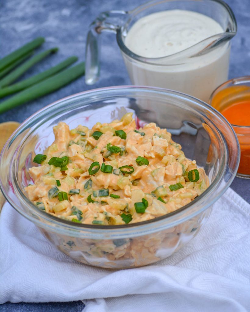 buffalo ranch chicken salad in a glass bowl topped with thinly sliced green onions