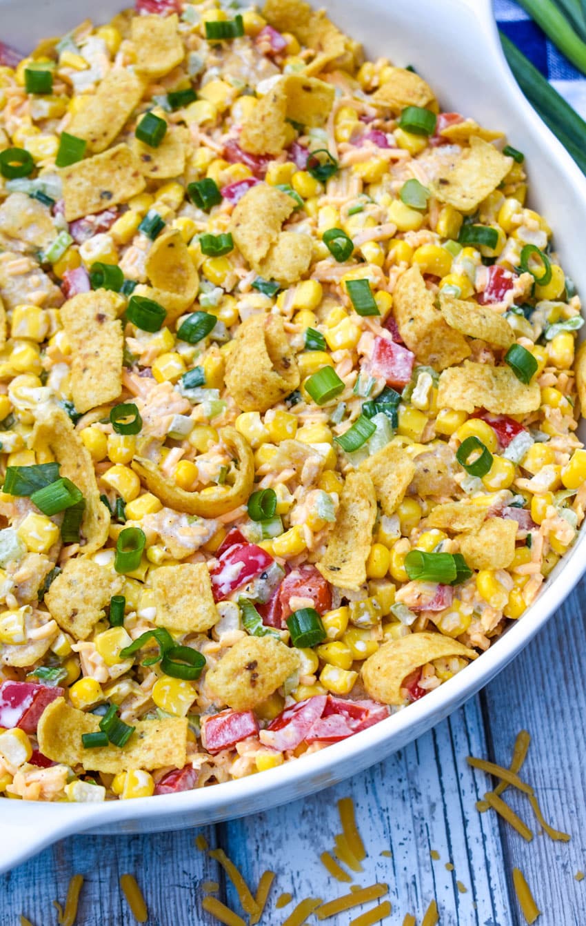 crunchy corn salad with fritos in a large white serving bowl with green onions on the side