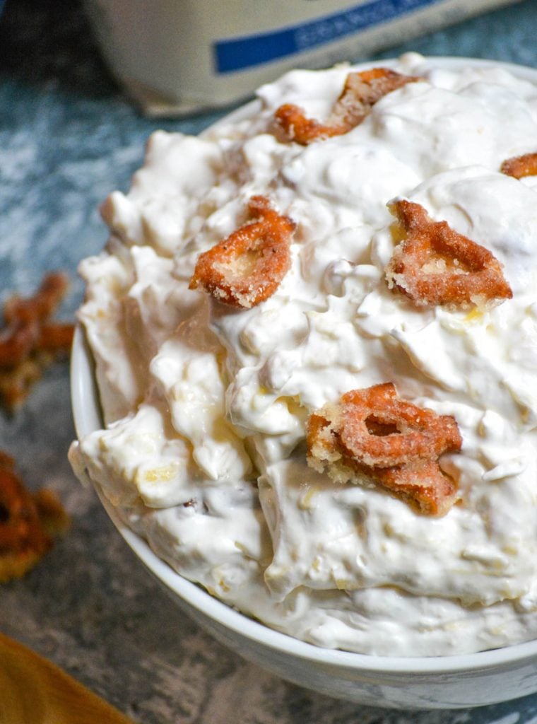 creamy dessert fluff salad is served in a white bowl with candied pretzel pieces on top for garnish, with a bag of Dixie Crystal's sugar in the back ground