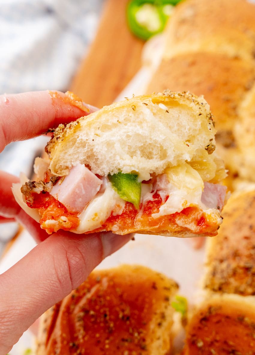 a hand holding up a hawaiian pizza slider