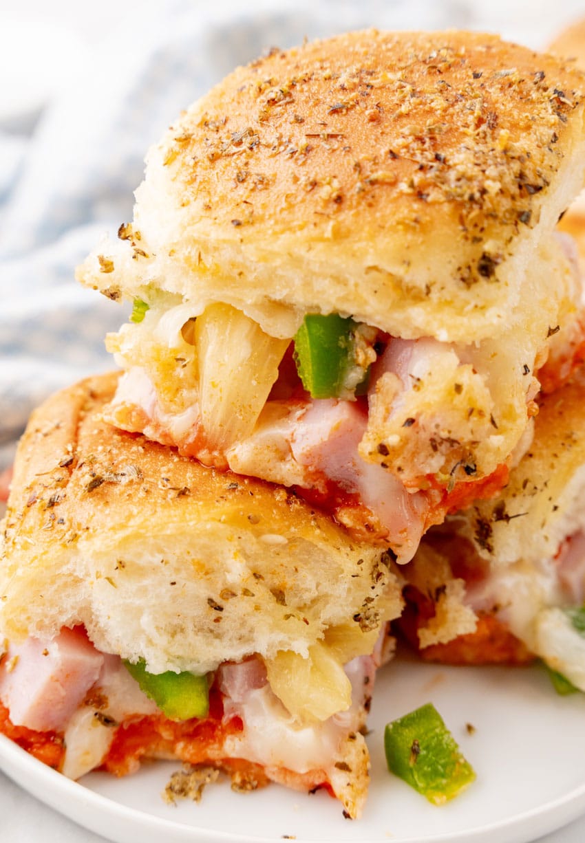 hawaiian pizza sliders stacked on a small white plate