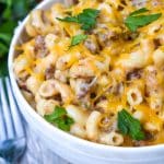 instant pot cheeseburger macaroni in a white bowl with two silver forks on the side