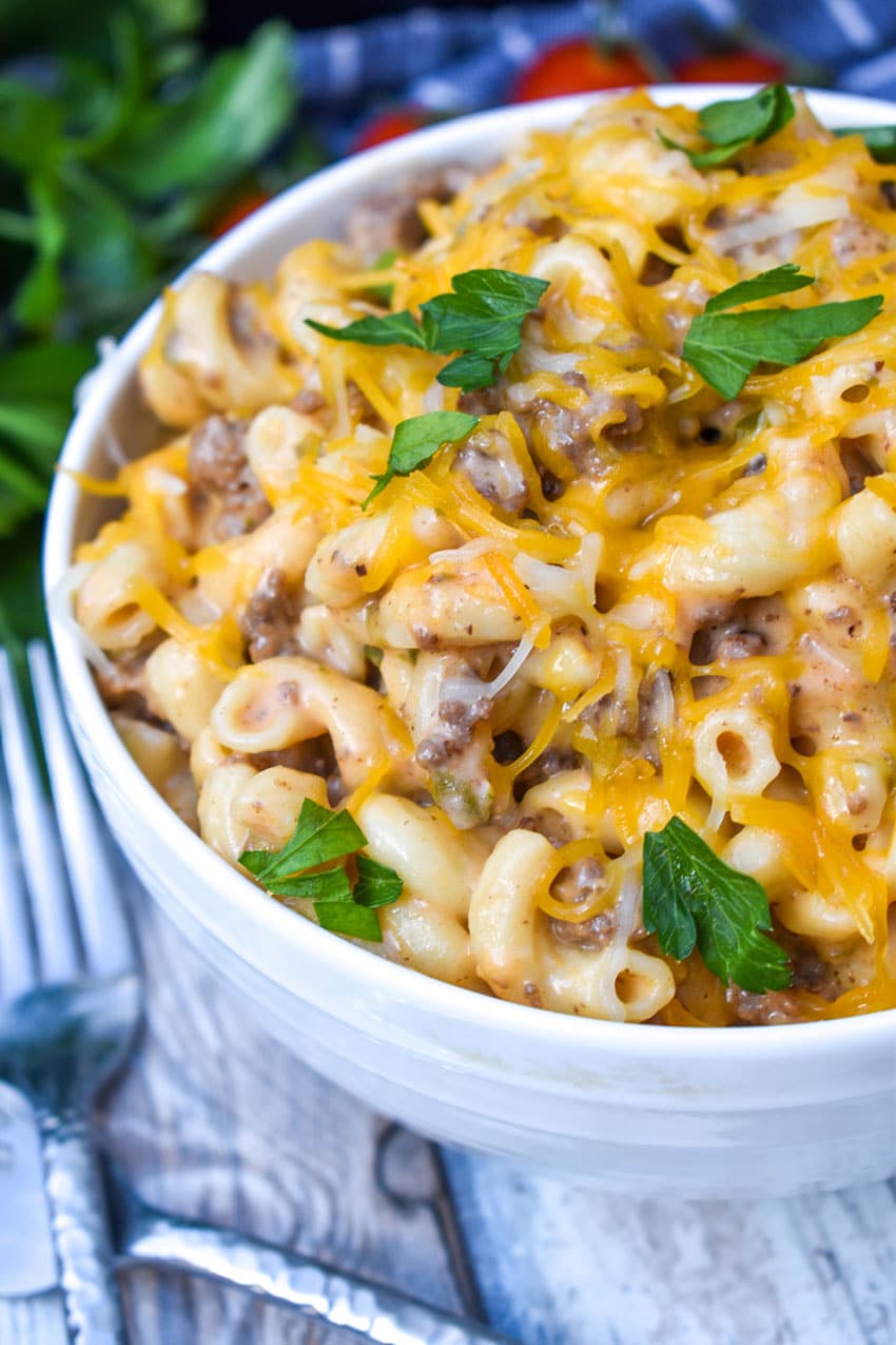 instant pot cheeseburger macaroni in a white bowl with two silver forks on the side