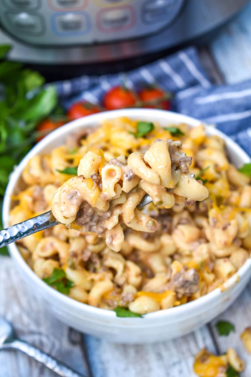 a silver fork stuck in a white bowl filled with instant pot cheeseburger pasta