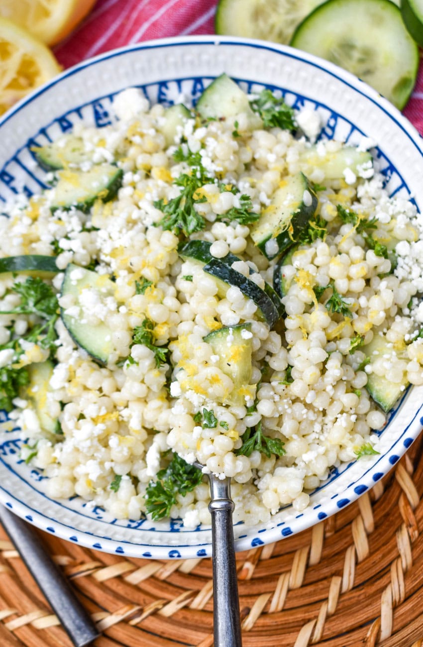 lemon couscous salad topped with crumbled feta cheese in a white bowl 