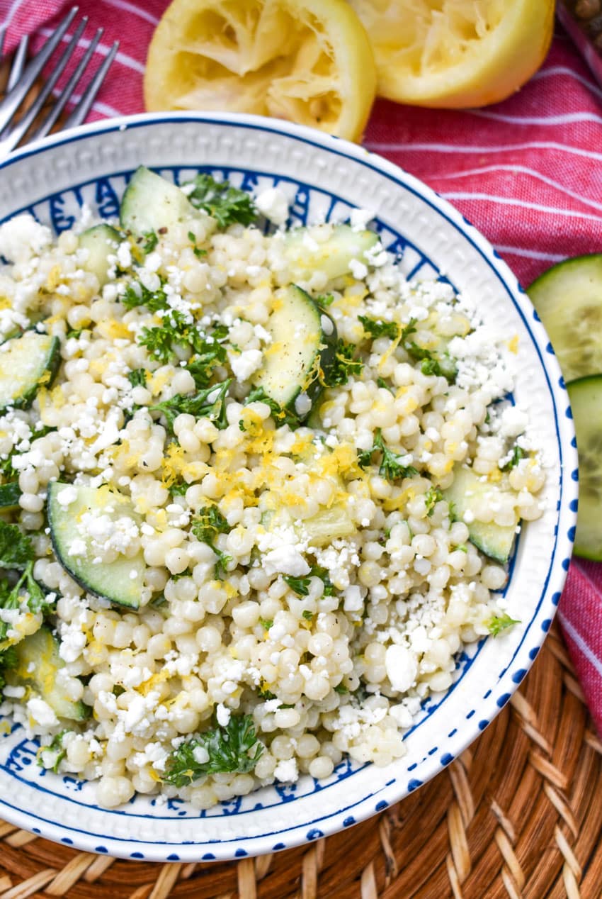 lemon couscous salad topped with crumbled feta cheese in a white bowl 