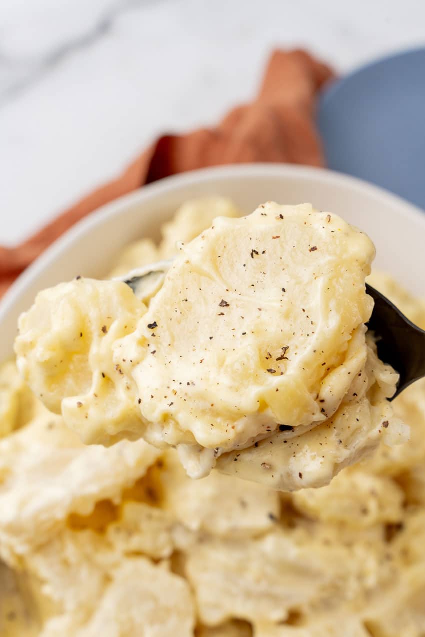 a spoon holding up a scoop of creamy southern potato salad