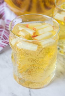APPLE CIDER SANGRIA IN A SMALL GLASS JAR WITH DICED APPLES FLOATING ON TOP FOR GARNISH