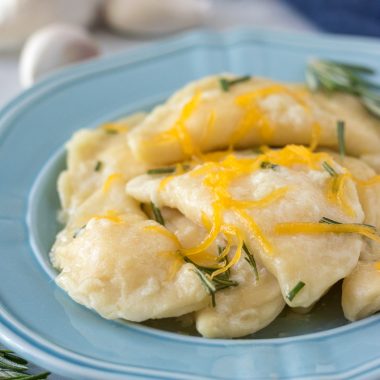 homemade cheddar cheese filled pierogi on a blue plate