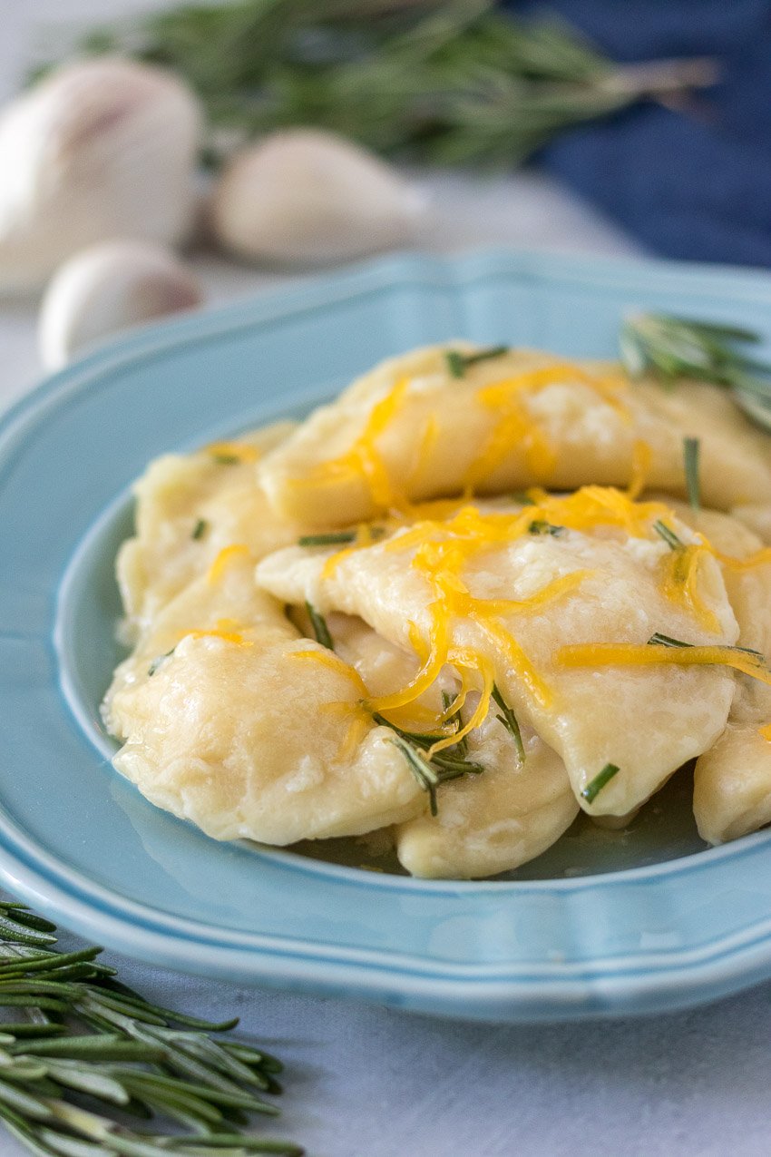 homemade cheddar cheese filled pierogi on a blue plate