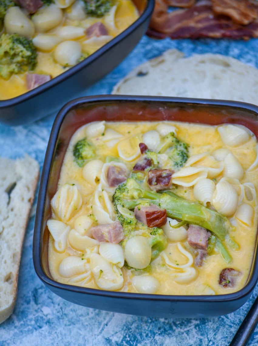 MAC AND CHEESE SOUP IN TWO BLACK BOWLS ON A BLUE COUNTERTOP