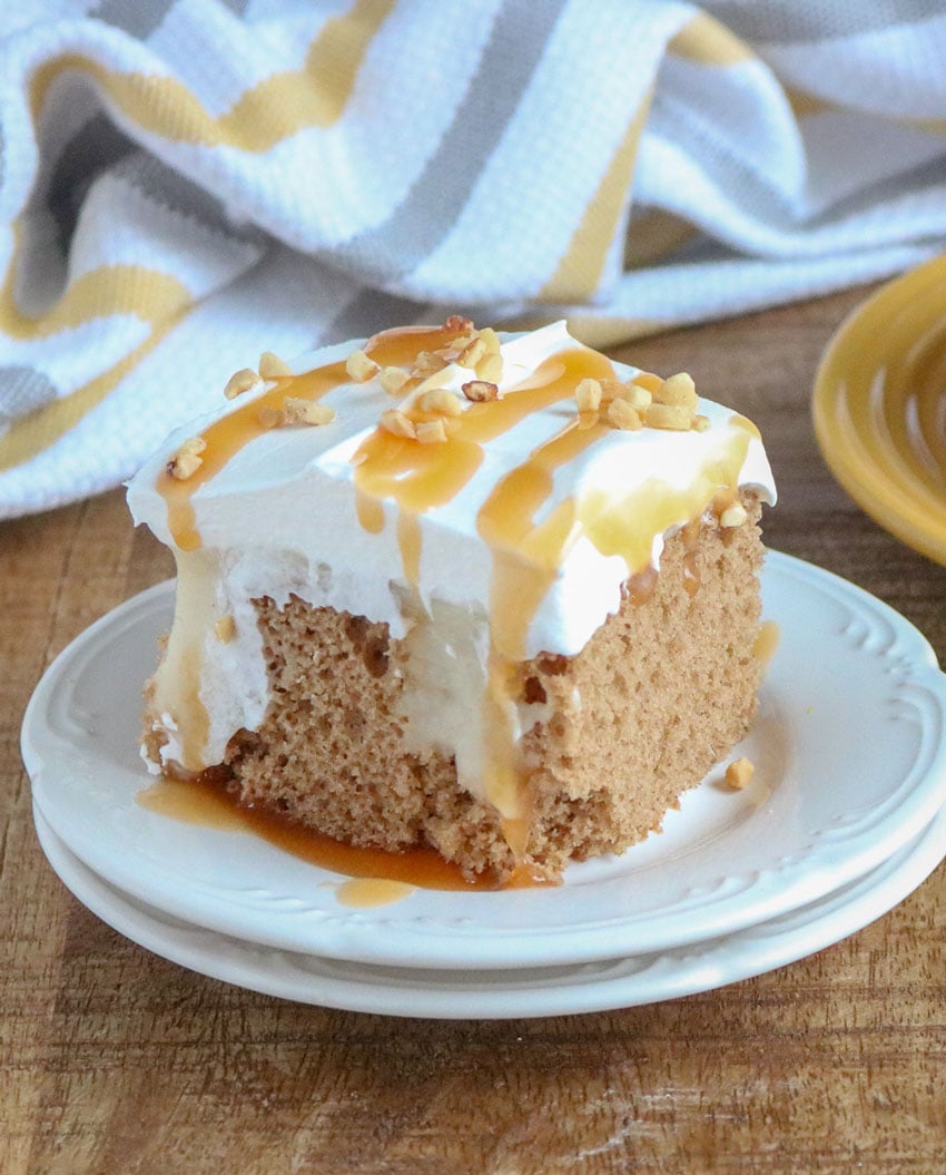 A SLICE OF APPLE SPICE POKE CAKE ON A SMALL WHITE PLATE