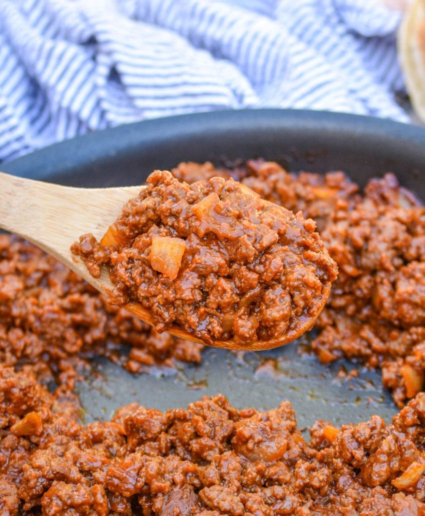 a wooden spoon holding up a scoop of the homemade sloppy joe sauce