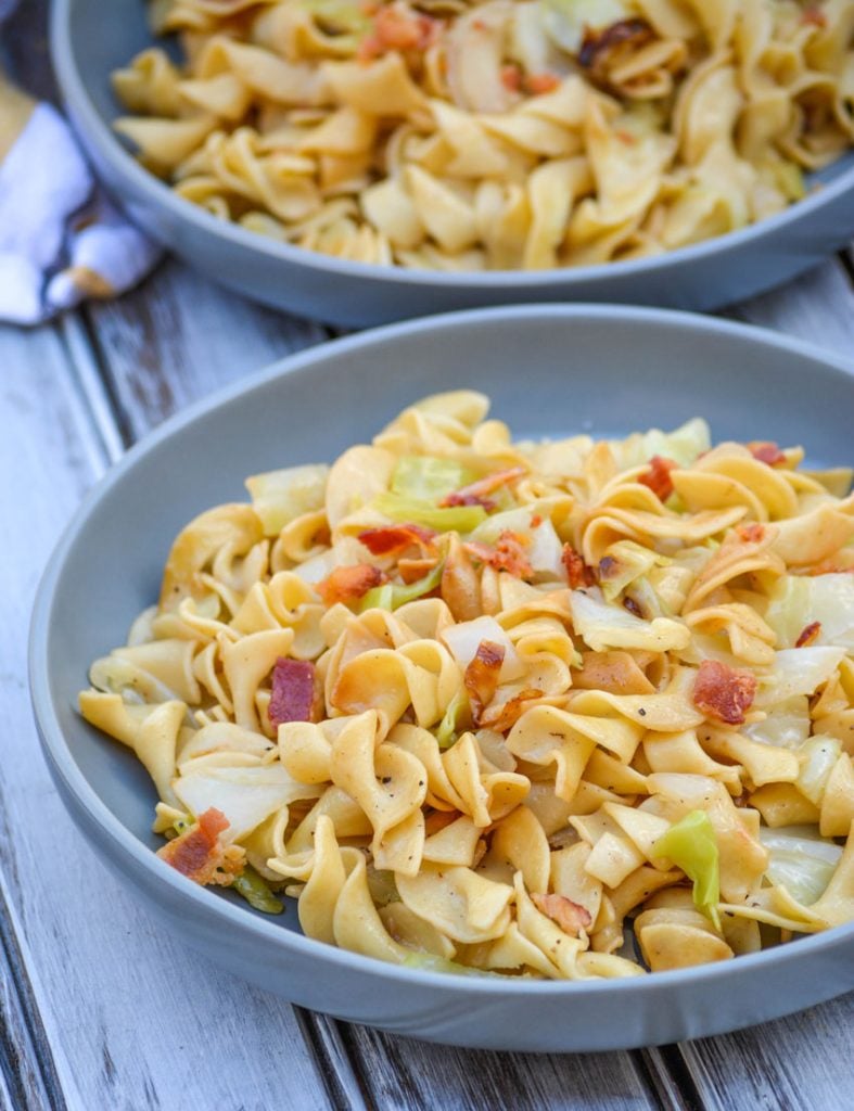 Haluski Recipe (Polish fried cabbage & noodles) topped with crisp, crumbled bacon and served on a large gray plate