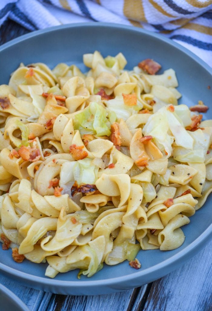 Haluski Recipe (Polish fried cabbage & noodles) topped with crisp, crumbled bacon and served on a large gray plate