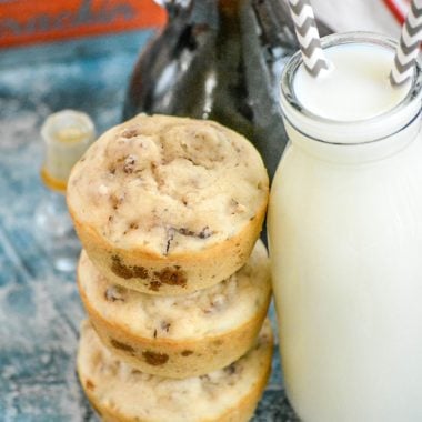 a stack of three sausage pancake muffins next to a glass carafe filled with milk