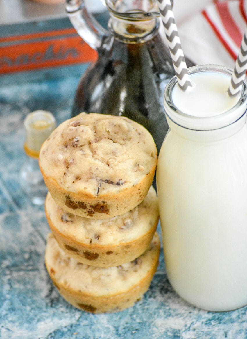 a stack of three sausage pancake muffins next to a glass carafe filled with milk