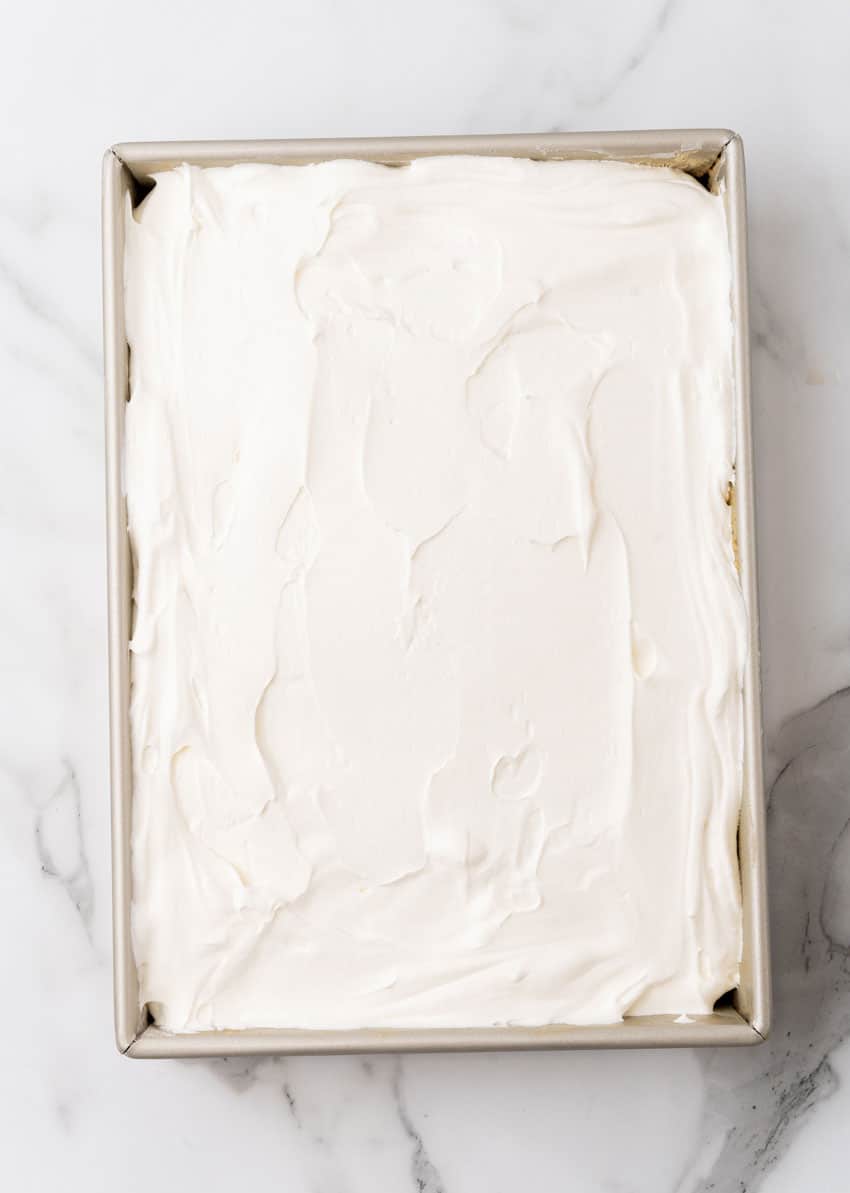 a layered apple spice poke cake in a large metal baking dish
