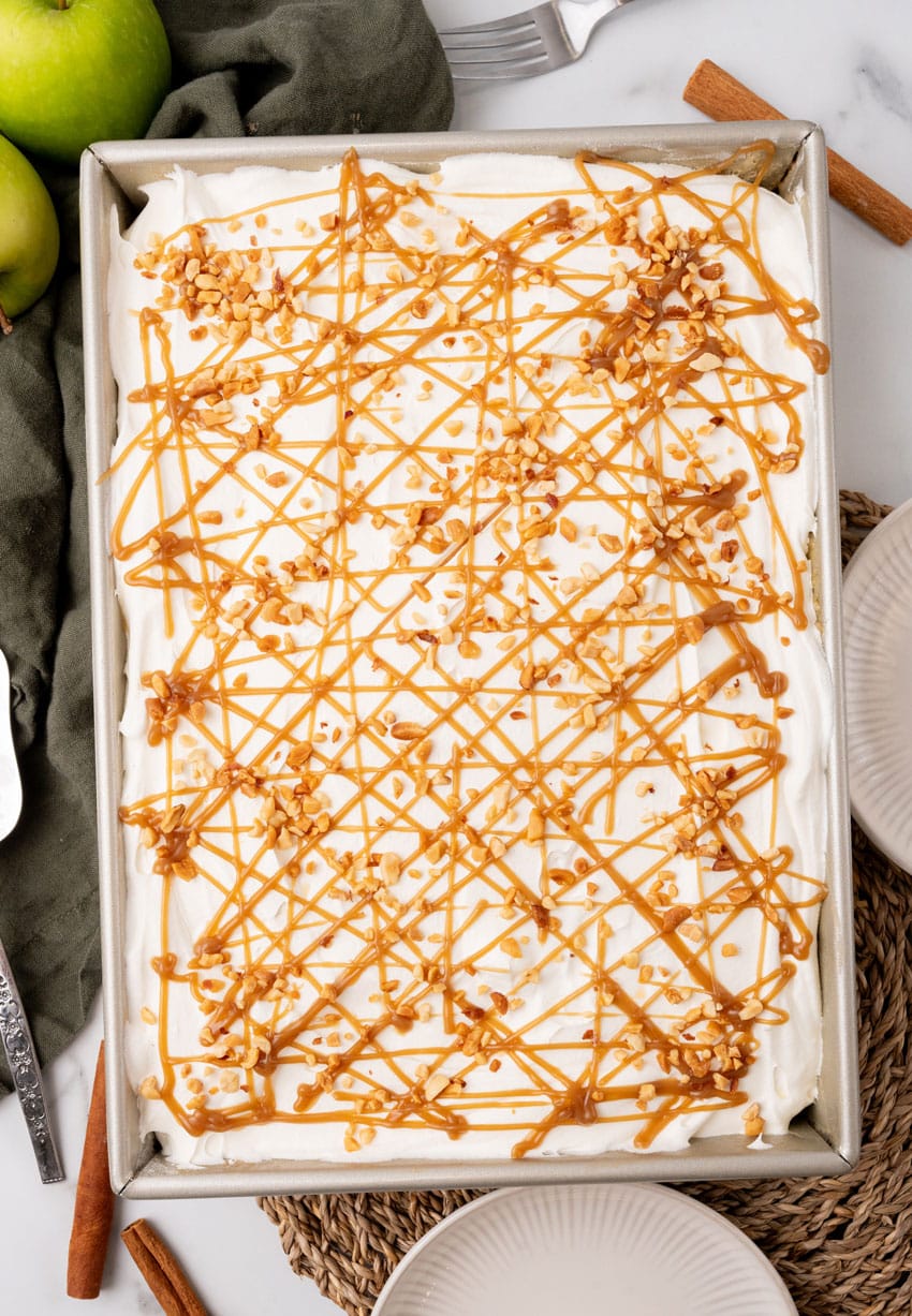 a layered apple spice poke cake in a large metal baking dish