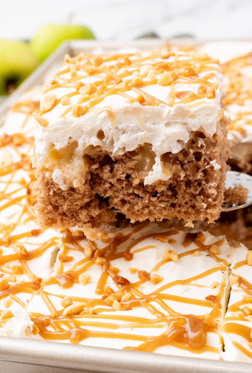 a silver spatula lifting up a slice of an apple spice poke cake