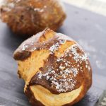 HOMEMADE PRETZEL ROLLS ON A BLACK CUTTING BOARD