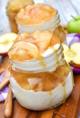 apple pie cheesecake parfaits drizzled with caramel sauce on a wooden cutting board