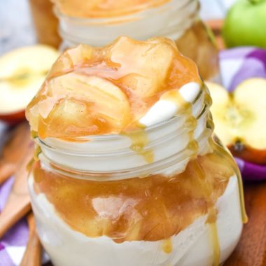 apple pie cheesecake parfaits drizzled with caramel sauce on a wooden cutting board