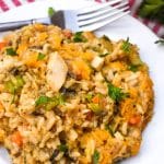 cheesy chicken and wild rice casserole on a white plate with a silver fork resting on the side
