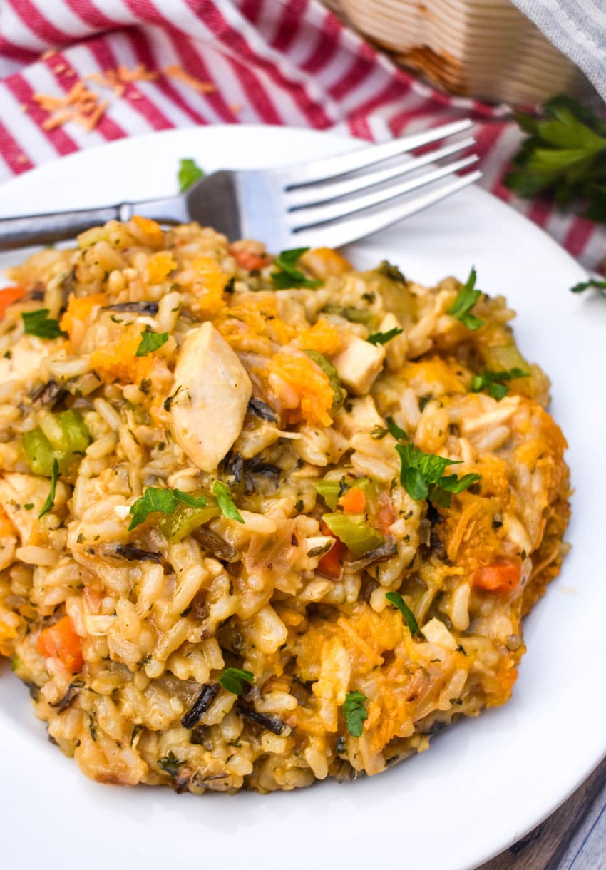 cheesy chicken and wild rice casserole on a white plate with a silver fork resting on the side