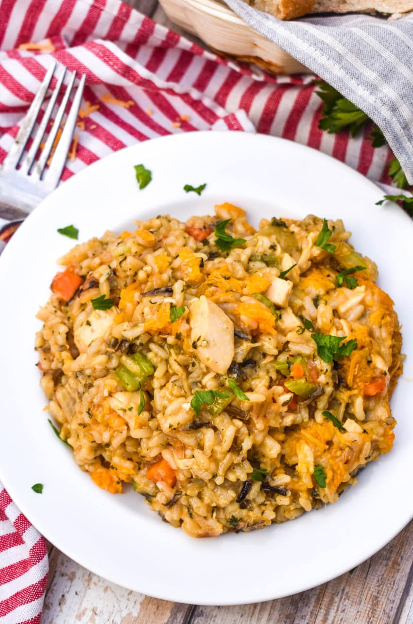 cheesy chicken and wild rice casserole on a white plate with a silver fork resting on the side