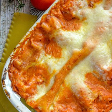 lasagna with a blush sauce in a white casserole dish