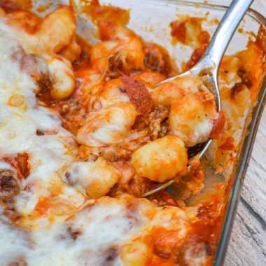 a silver spoon scooping pepperoni pizza gnocchi bake out of a glass casserole dish